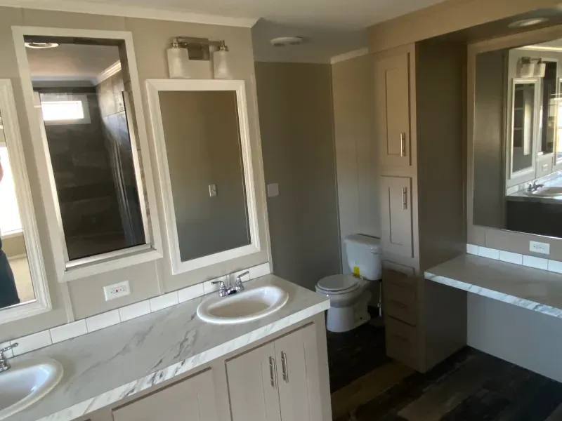 A bathroom with two sinks , a toilet and two mirrors.