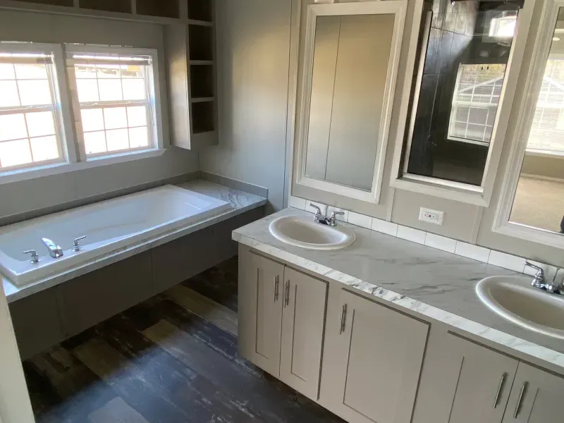 A bathroom with two sinks , a tub and two mirrors.
