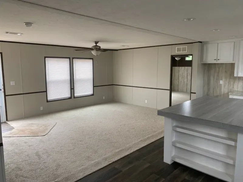 An empty living room in a mobile home with a ceiling fan