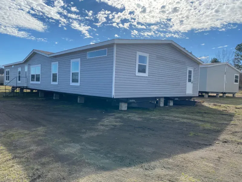 A mobile home is sitting on top of a dirt field.