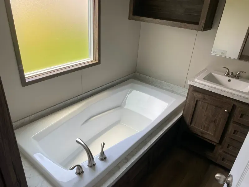 A bathroom with a bathtub , sink and window.