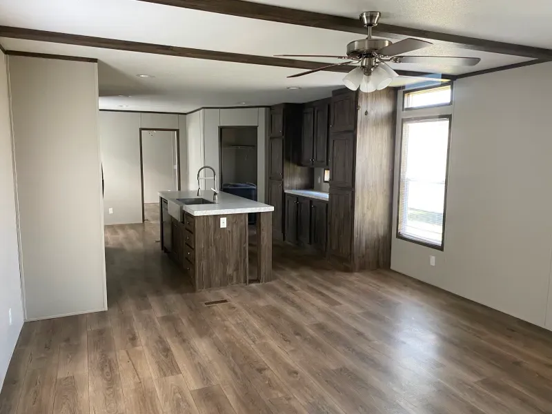 A living room in a mobile home with hardwood floors and a ceiling fan.