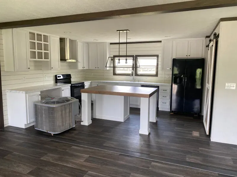 A kitchen with white cabinets and a black refrigerator.