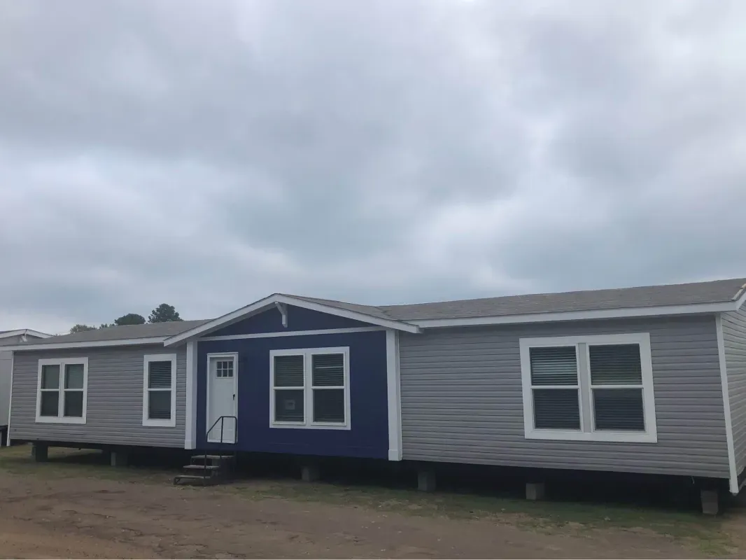 A mobile home with a blue roof is parked in a field.