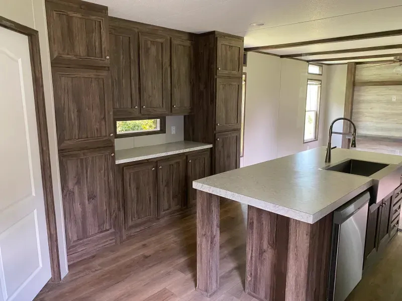 A kitchen with wooden cabinets , a sink , and a window.