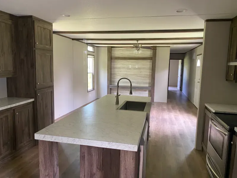 A kitchen in a mobile home with a large island and a sink.