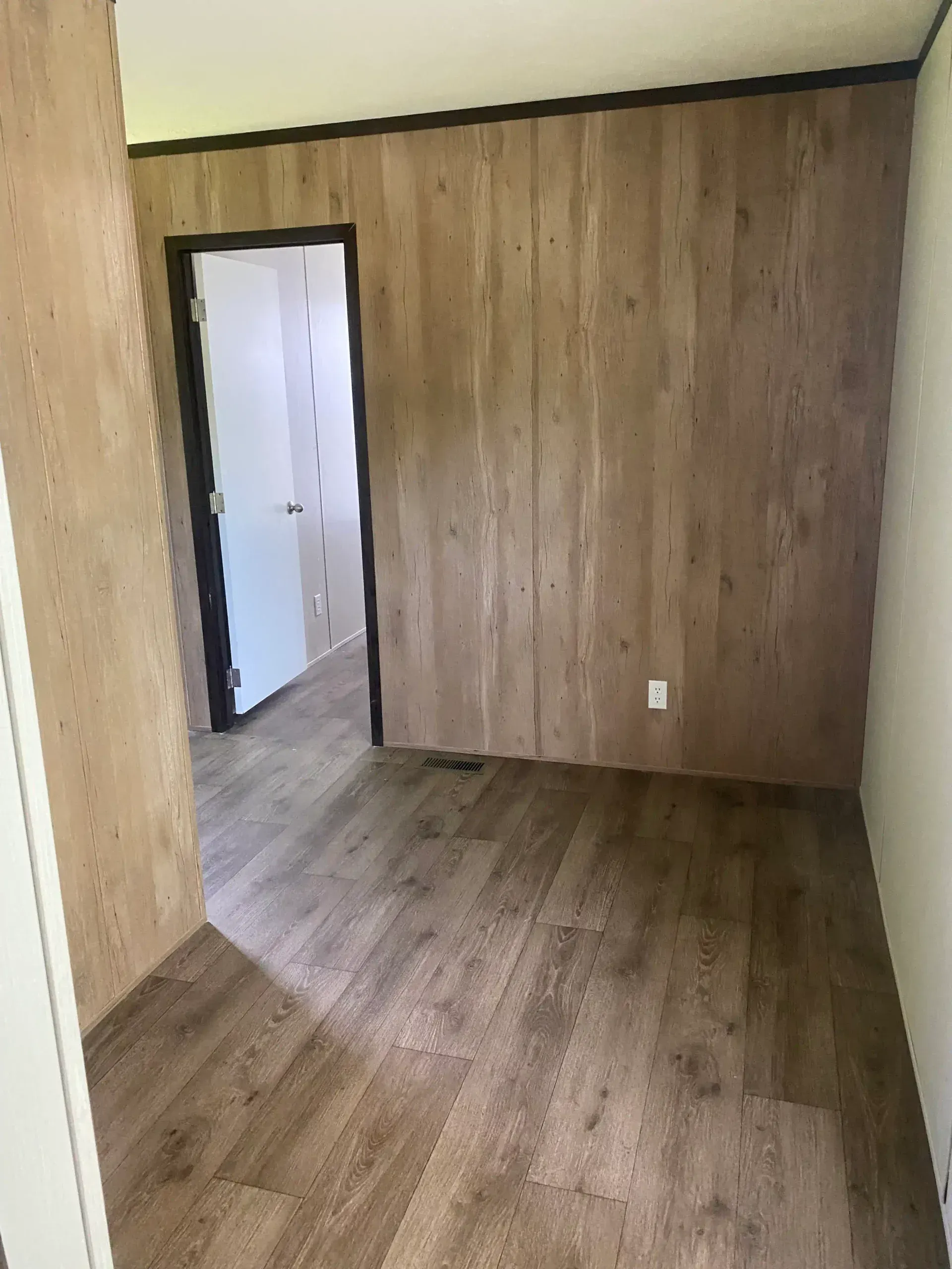 A room with hardwood floors and wood paneling on the walls.
