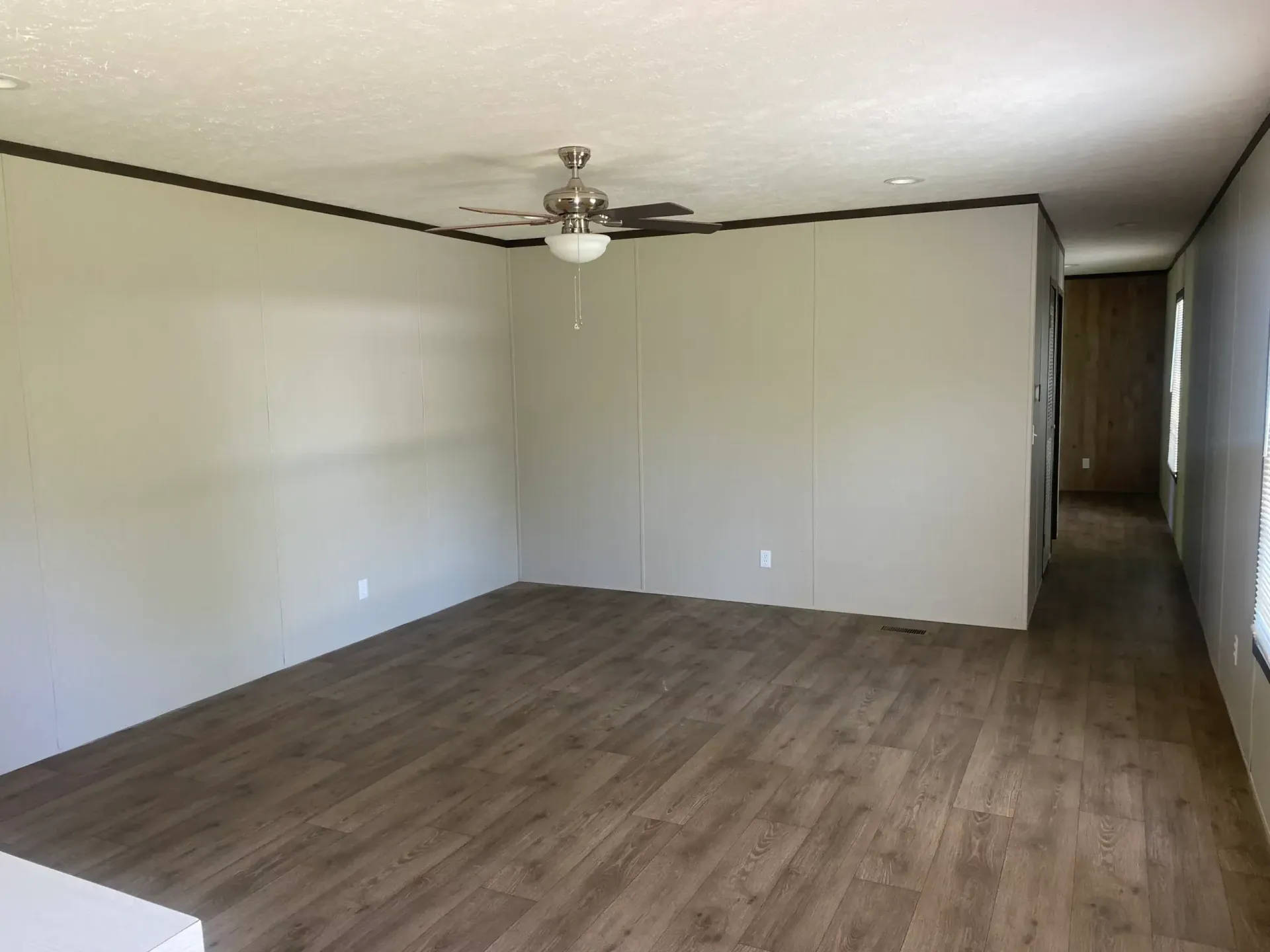 An empty living room with hardwood floors and a ceiling fan.