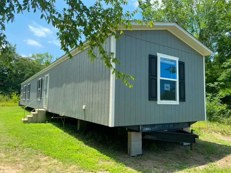 A mobile home is parked in a grassy field.
