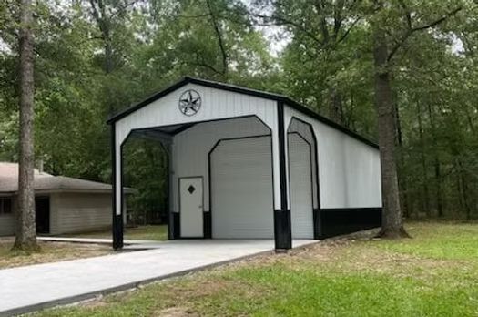 A white and black garage with a texas star on it is sitting in the middle of a lush green field.