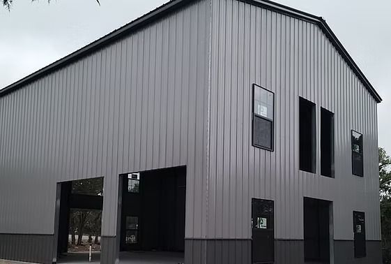 A large gray metal building with a black roof and windows.