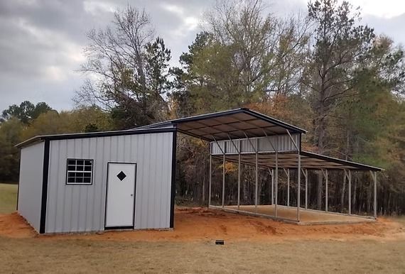 There is a shed and a carport in the middle of a field.