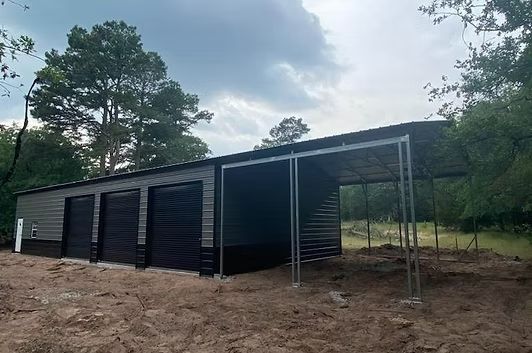 A black metal garage with a canopy is sitting in the middle of a dirt field.