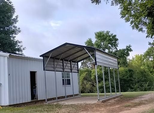 A white building with a carport attached to it.