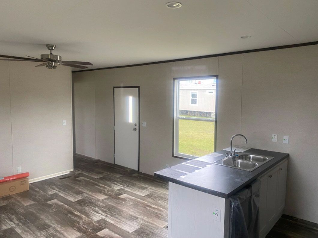 A kitchen in a mobile home with a sink and a ceiling fan.