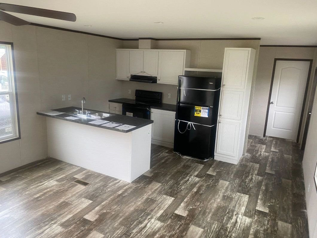 A kitchen in a mobile home with a refrigerator , sink , and stove.