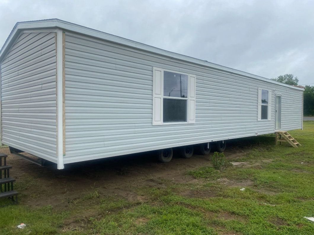 A mobile home is parked in a grassy field.