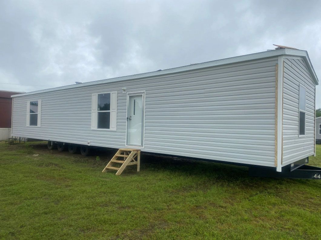 A white mobile home is parked in a grassy field.