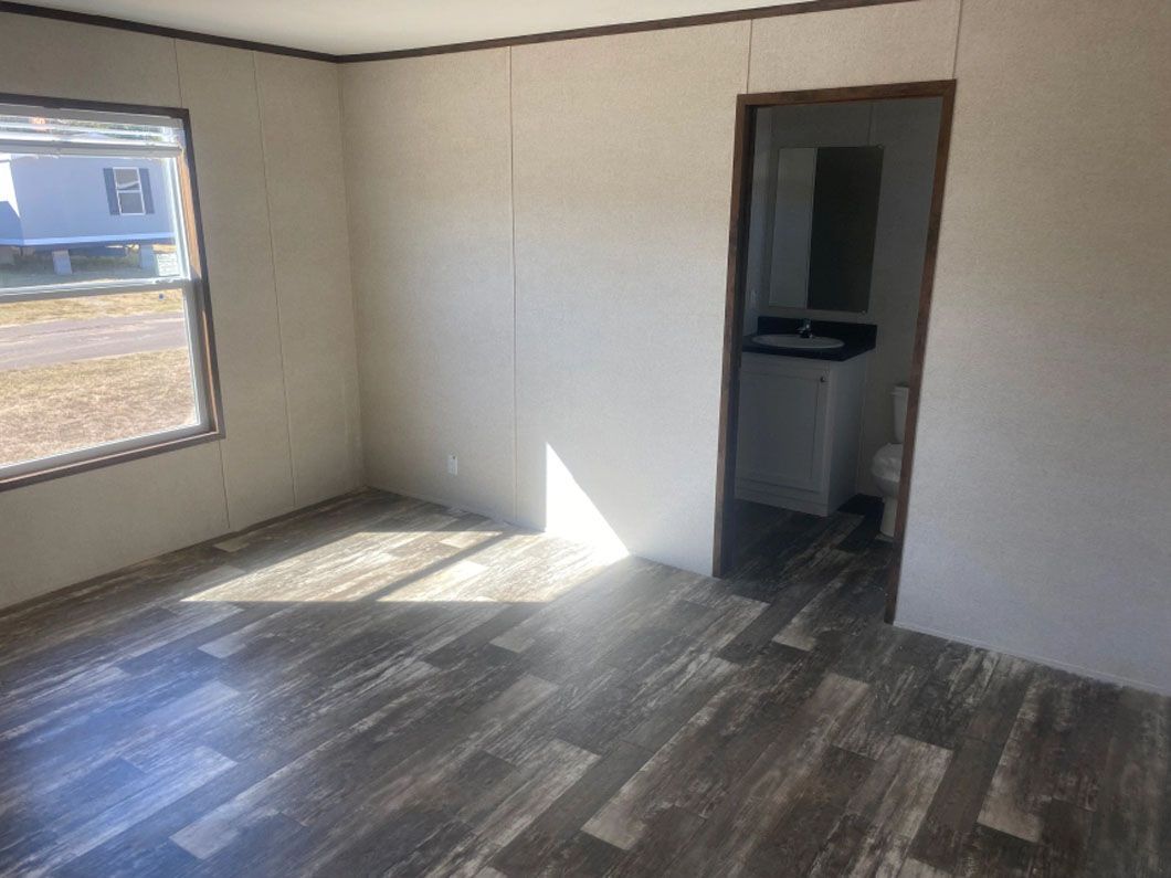 An empty room with a wooden floor and a window.