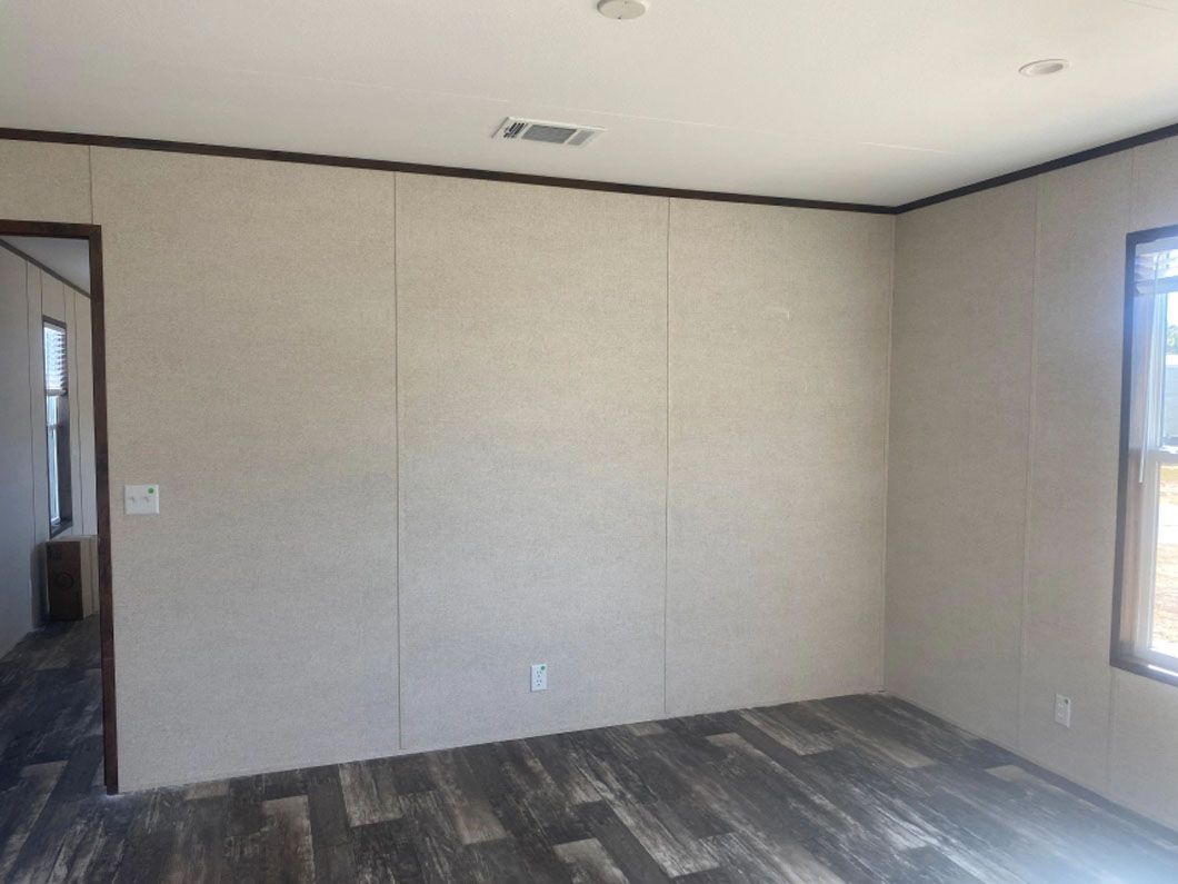 An empty room with a wooden floor and a white wall.