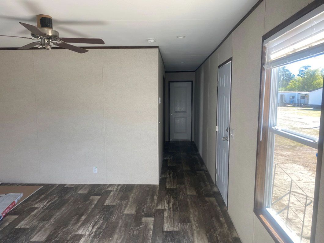 An empty room with a ceiling fan and a window.