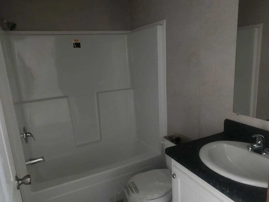 A bathroom with a tub , toilet , sink and mirror.