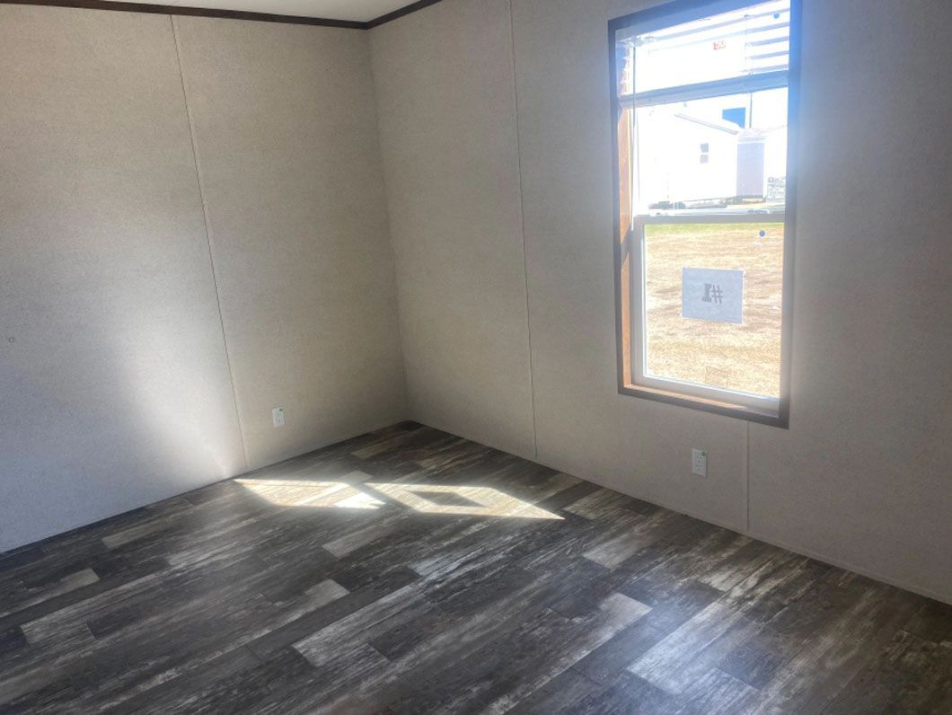 An empty room with a wooden floor and a window.
