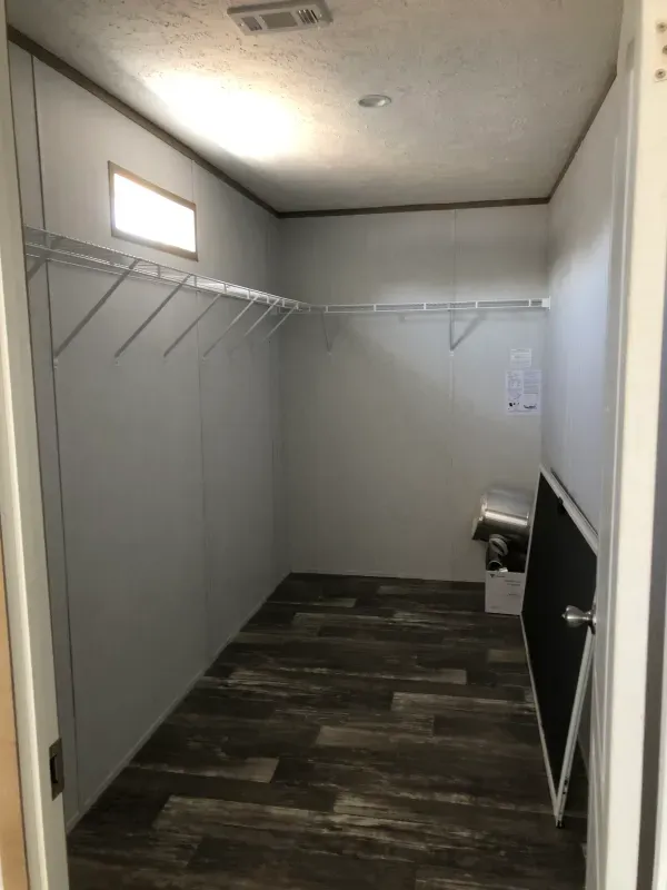 A walk in closet with lots of shelves and a window.