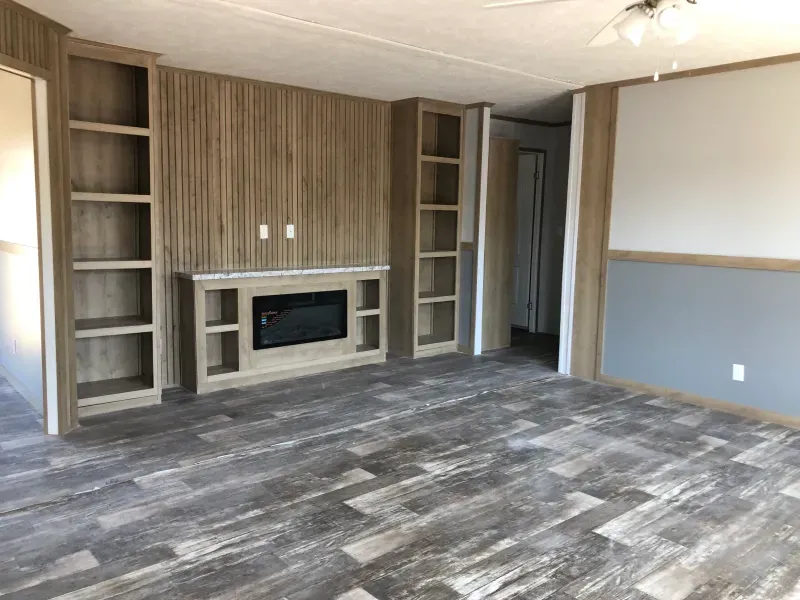 An empty living room with a fireplace and shelves.
