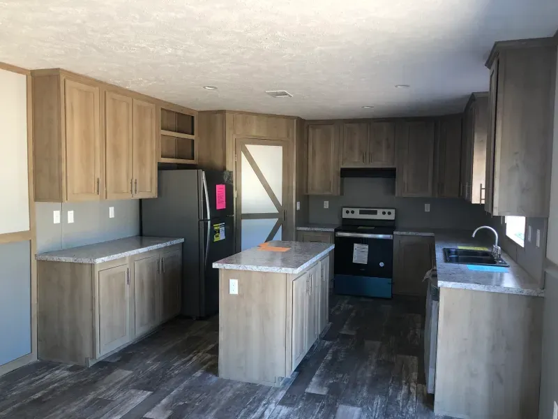 A kitchen with a refrigerator , stove , sink and cabinets.