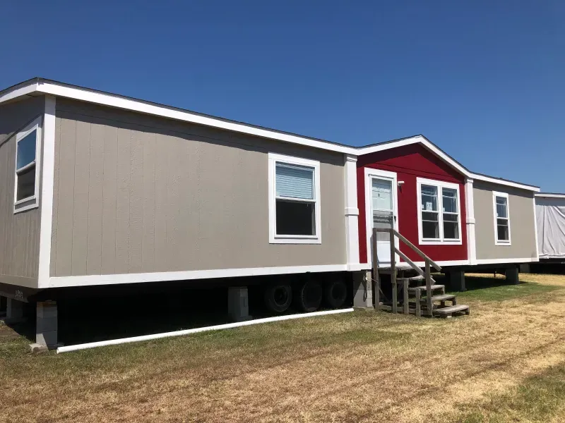 A mobile home with stairs leading up to it is sitting on top of a lush green field.