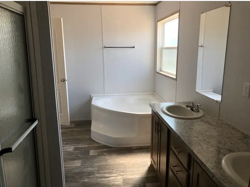 A bathroom with a tub , sink and mirror.