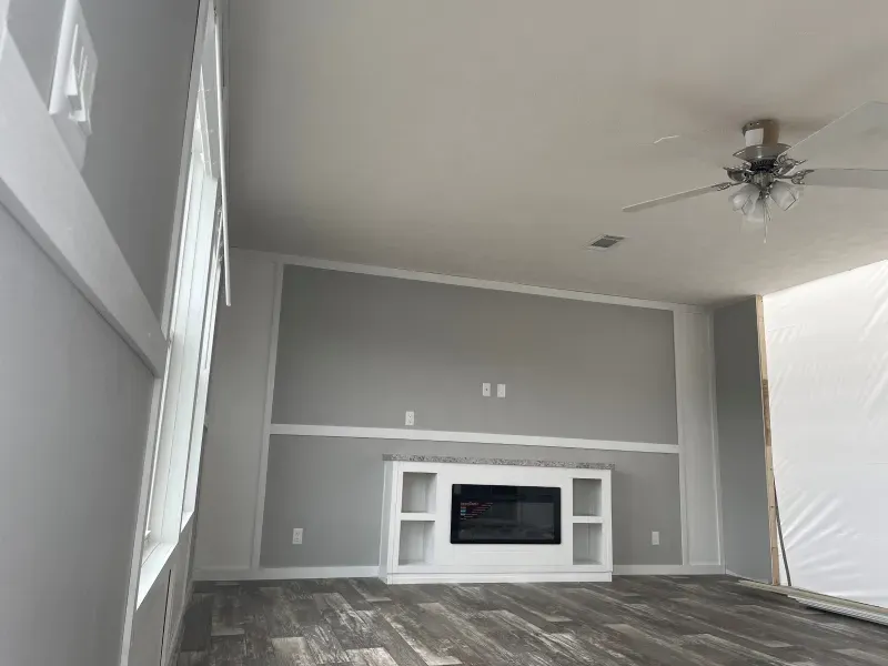 A living room with a fireplace and a ceiling fan.