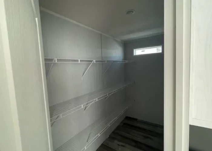 A walk in closet with lots of shelves and a window.