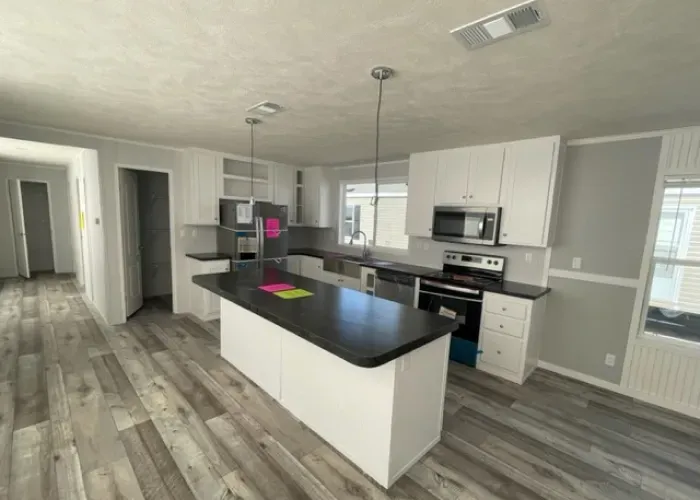 A kitchen in a mobile home with a large island in the middle.