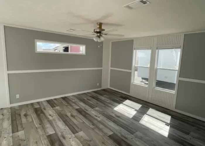 There is a ceiling fan in the room with a lot of windows.