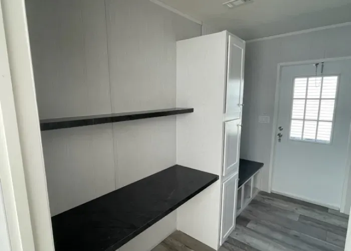 A hallway with a desk and shelves in a mobile home.