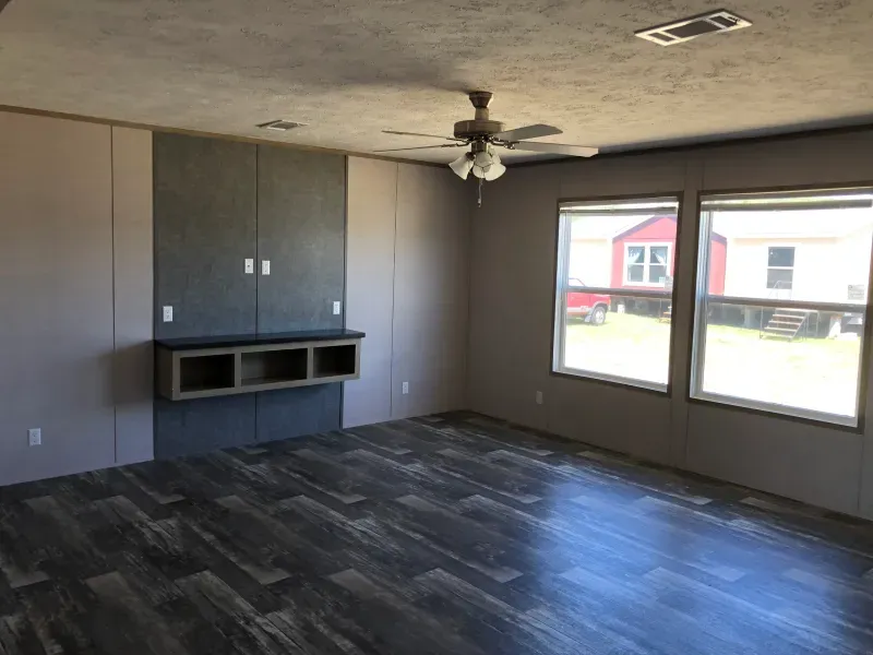 An empty living room with hardwood floors and a ceiling fan.