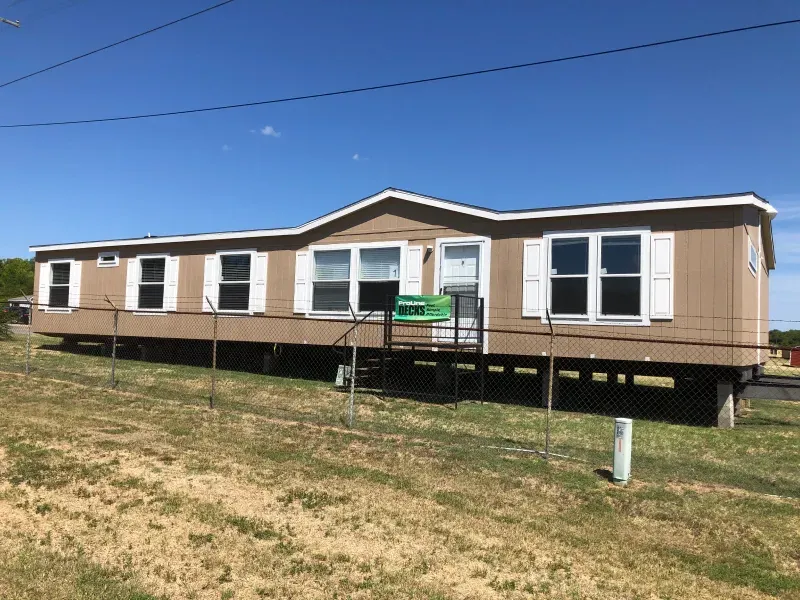 A mobile home is sitting in the middle of a grassy field.