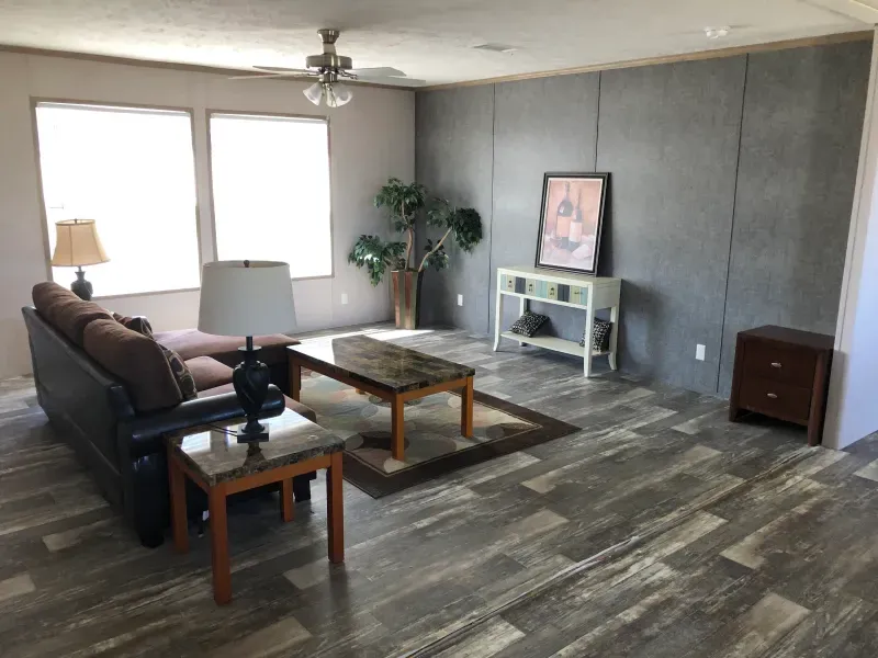 A living room with a couch , coffee table , lamps and a ceiling fan.