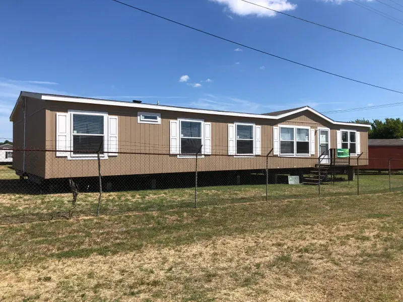 A mobile home is parked in the middle of a grassy field.