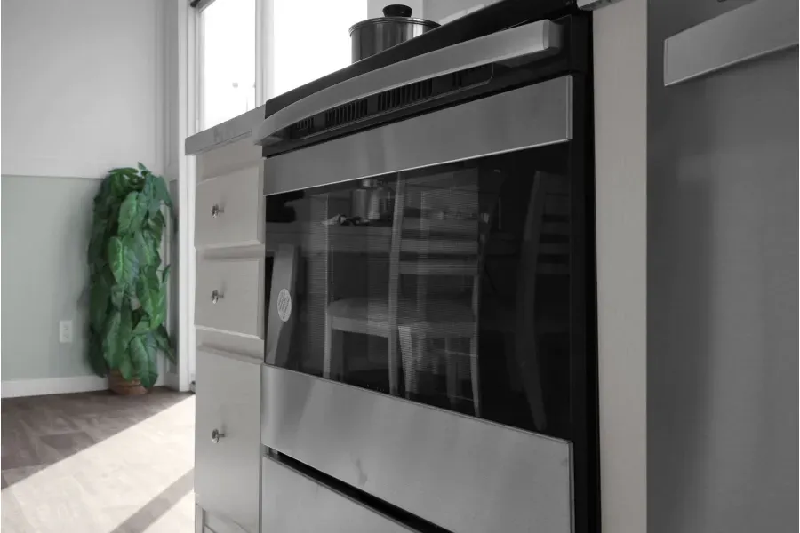 A stainless steel oven is sitting in a kitchen next to a window.