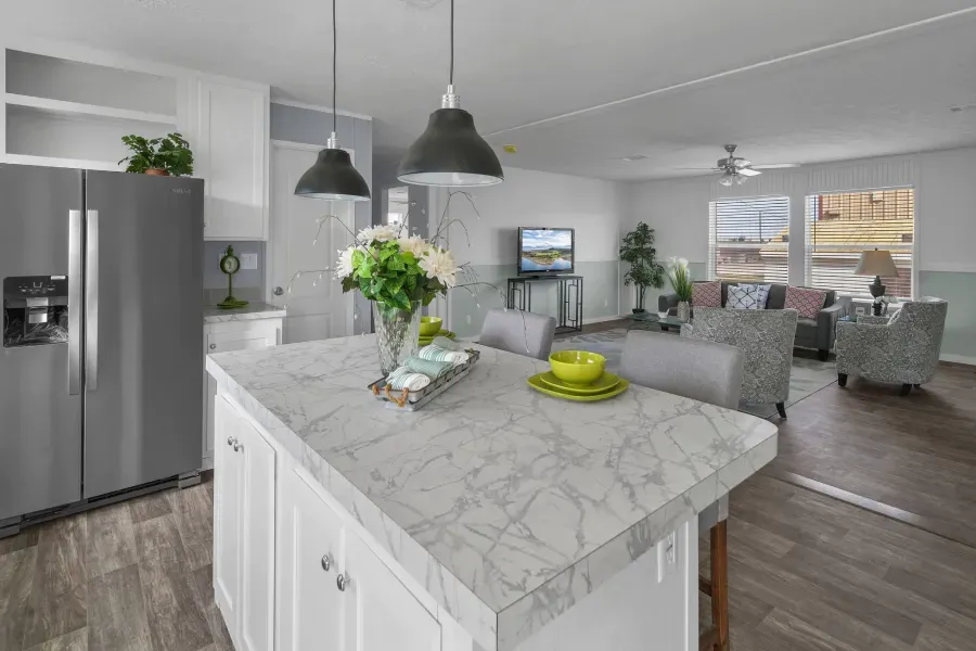 A kitchen with a large island and a stainless steel refrigerator.