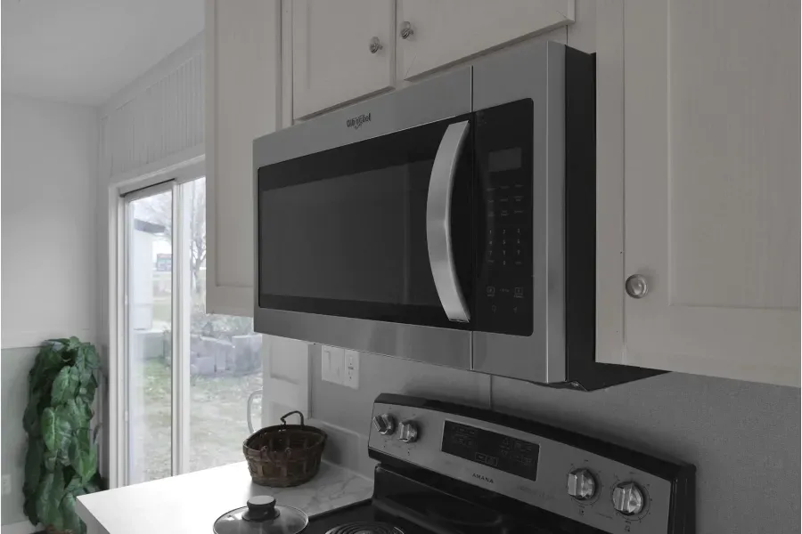 A microwave oven is mounted above a stove in a kitchen.