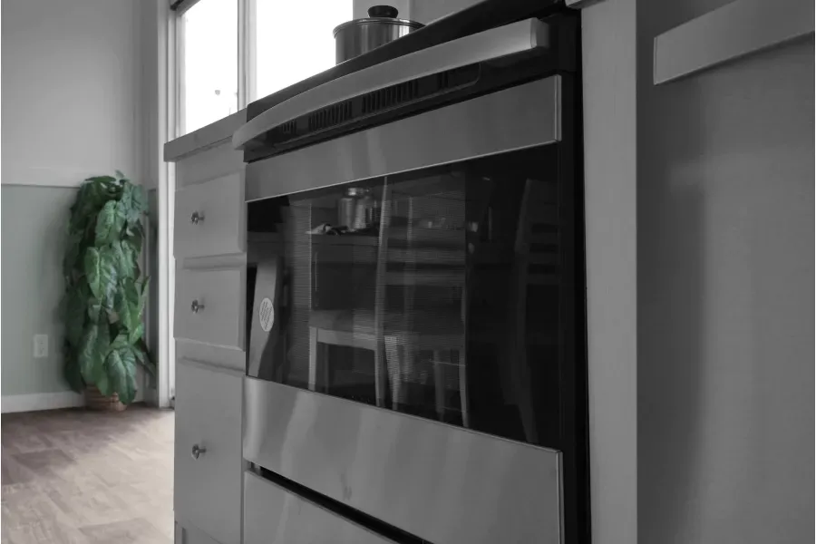 A stainless steel oven is sitting in a kitchen next to a window.