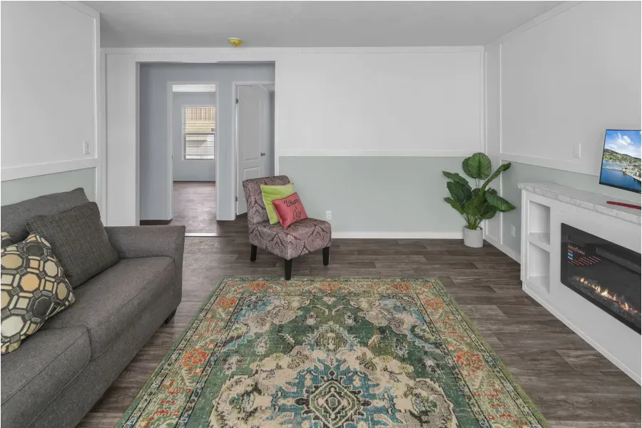 A living room with a couch , chair , rug and fireplace.
