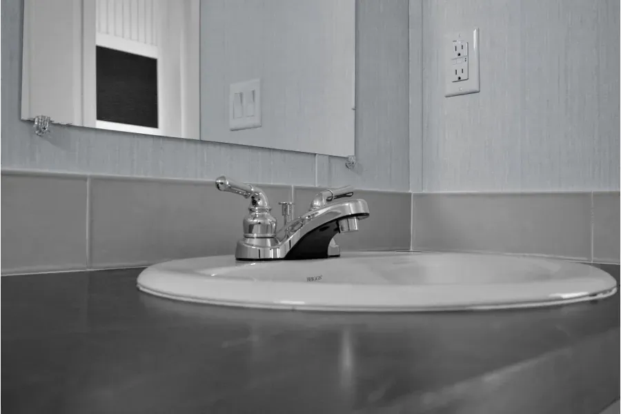 A bathroom sink with a faucet and a mirror.