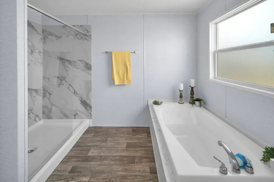 A bathroom with a tub , sink , shower and window.