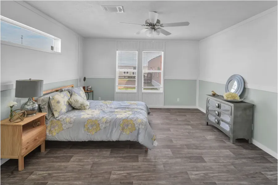 A bedroom with a bed , dresser , nightstand and ceiling fan.