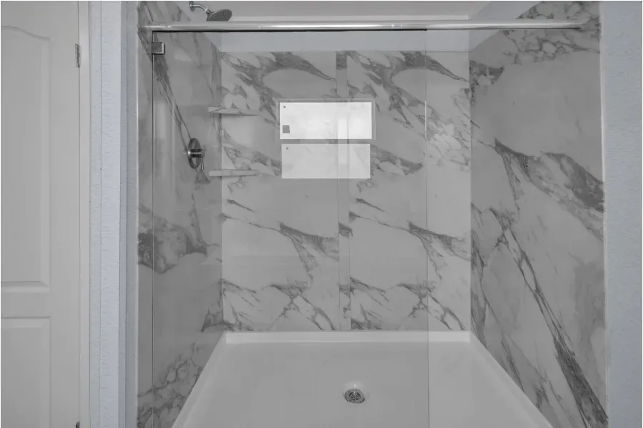 A black and white photo of a bathroom with marble tiles and a bathtub.